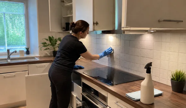 Köögi süvapuhastus, koristaja peseb pliidi kohal seinaplaate, õhupuhasti filter pannakse leotusse kohe töö alguses.