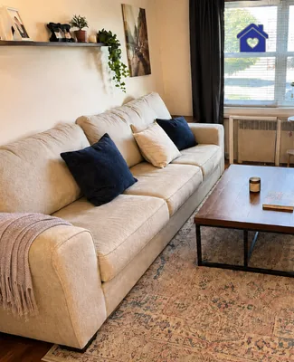 The same living room after a deep cleaning, the sofa cushions are arranged and the coffee table is in order, the lower surface of the glass top of the coffee table is also washed because the stains show through.